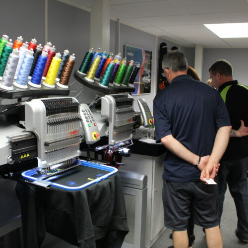 People looking at Melco EMT16X Embroidery machines in demo room People looking at Melco EMT16X Embroidery machines in demo room